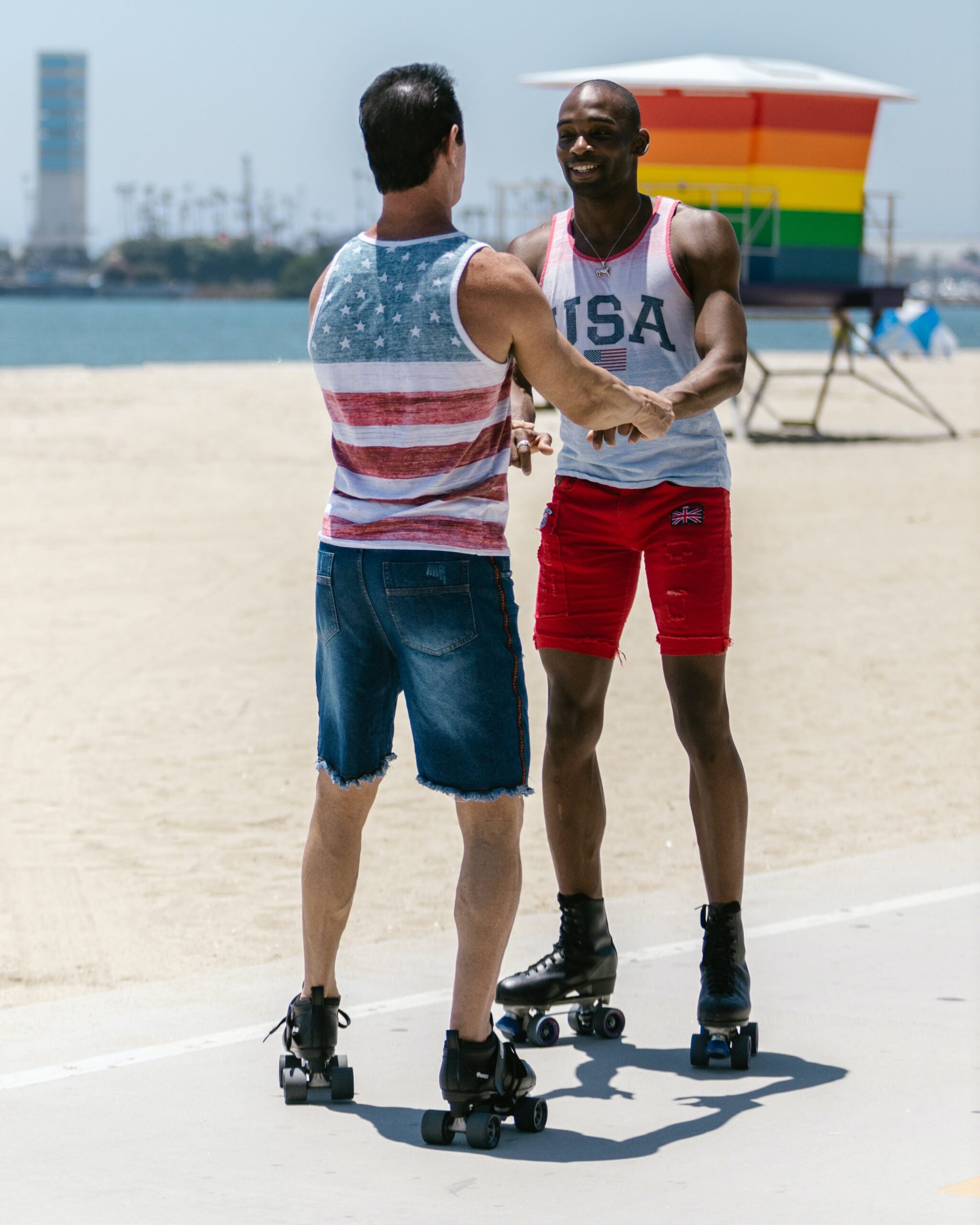 gay couple rollerblading on the beach holding hands