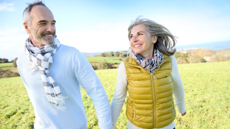 older white couple holding hands in a field