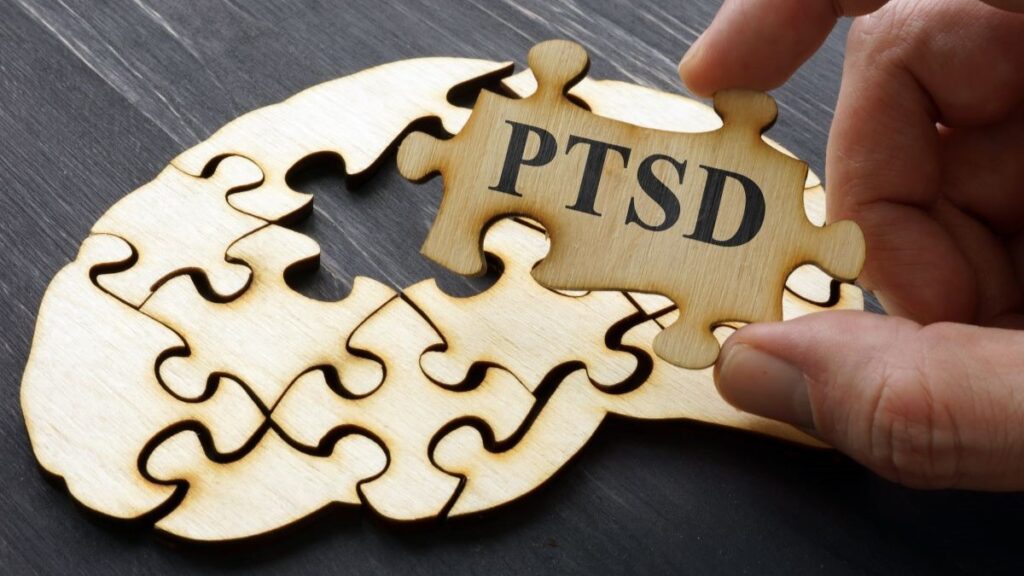 PTSD on a puzzle piece held by a hand about to be put into a puzzle formed to look like a brain