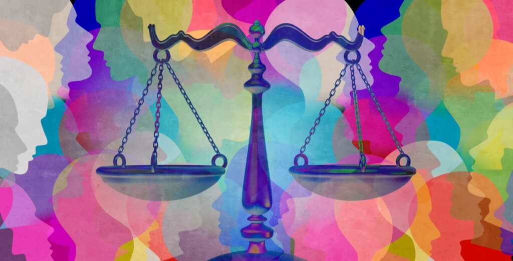 Scales representing social justice in front a a colorful background made of up different colored shapes representing human heads