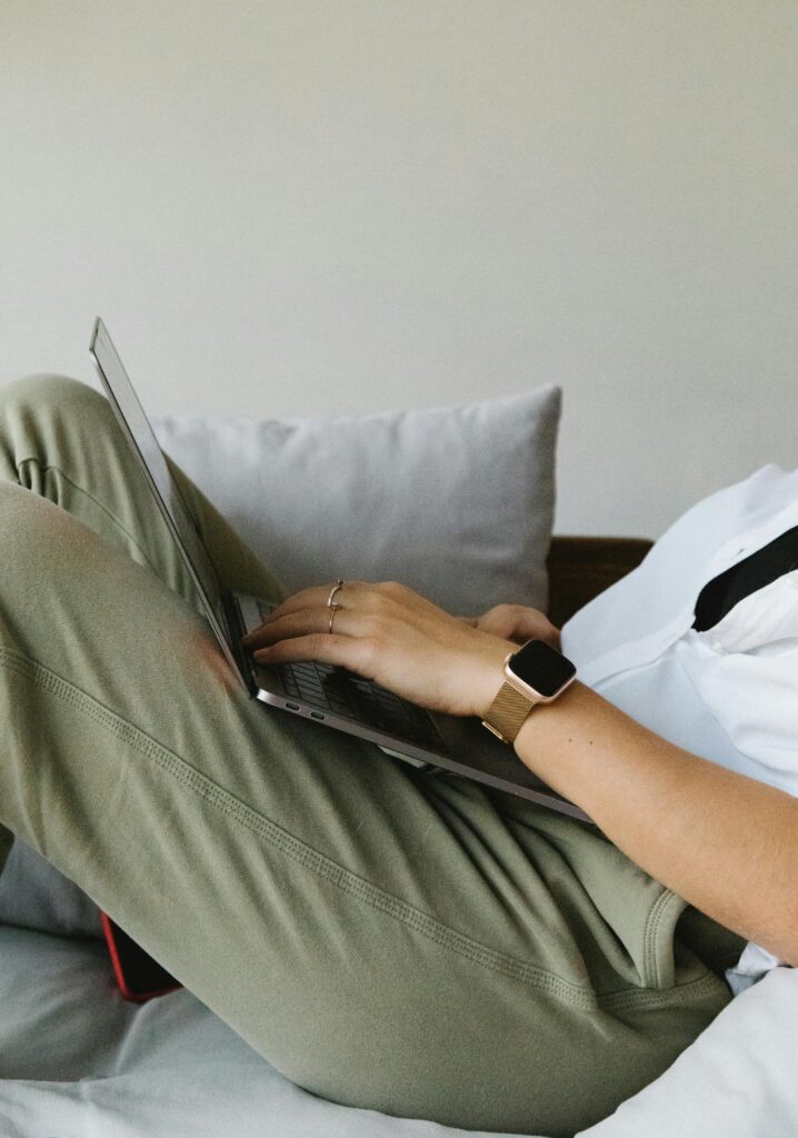 A woman in light green pants is sitting with her laptop. 