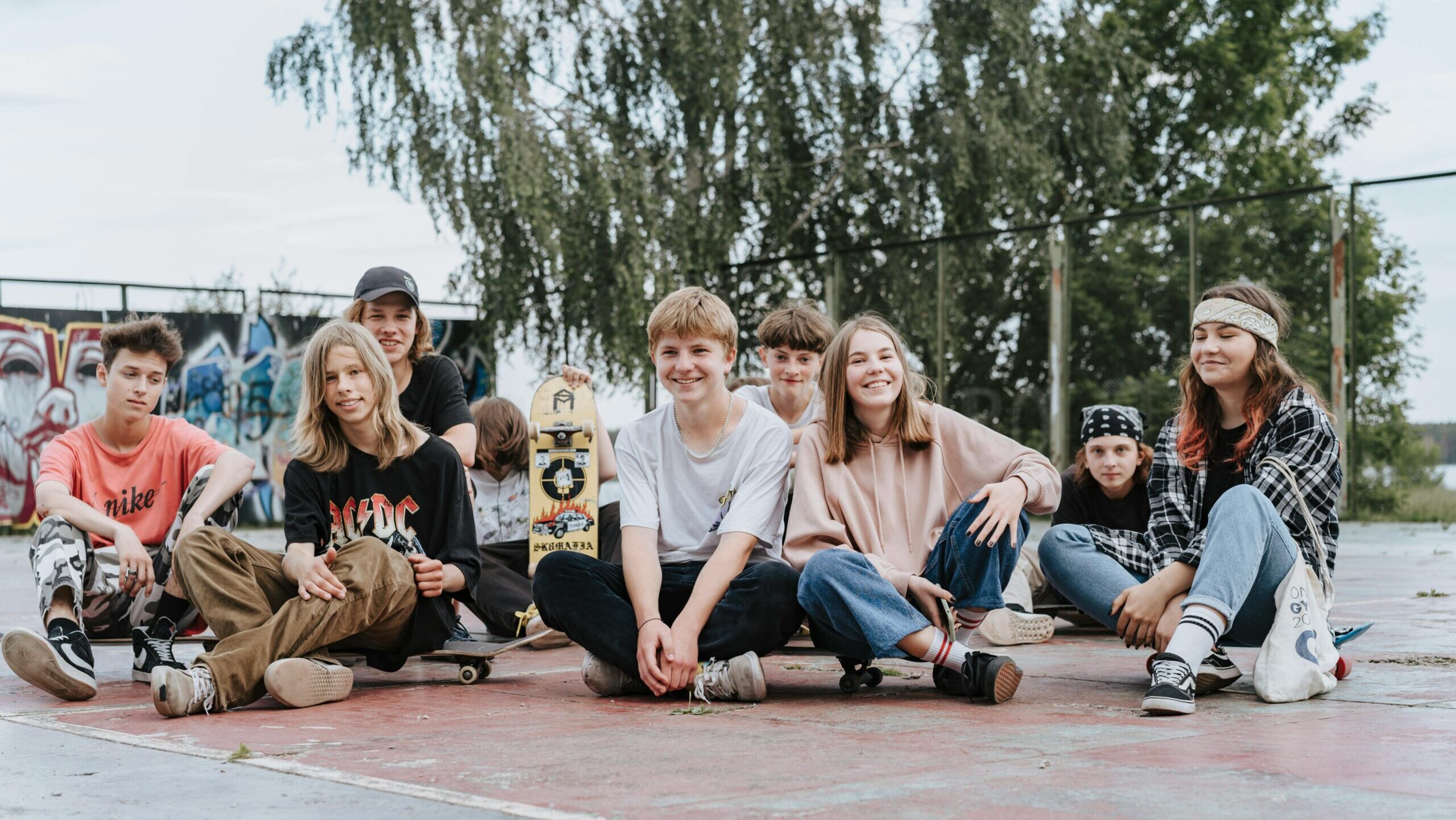 group of teens sitting outside in a basketball court