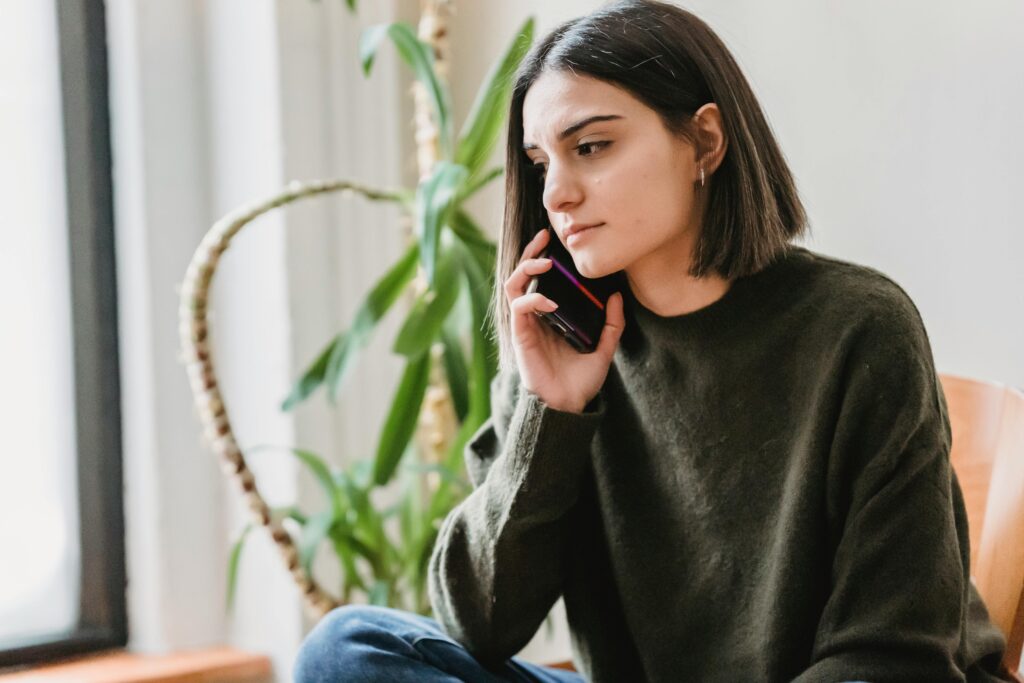 A sad looking female is on the phone with her digital therapist. 