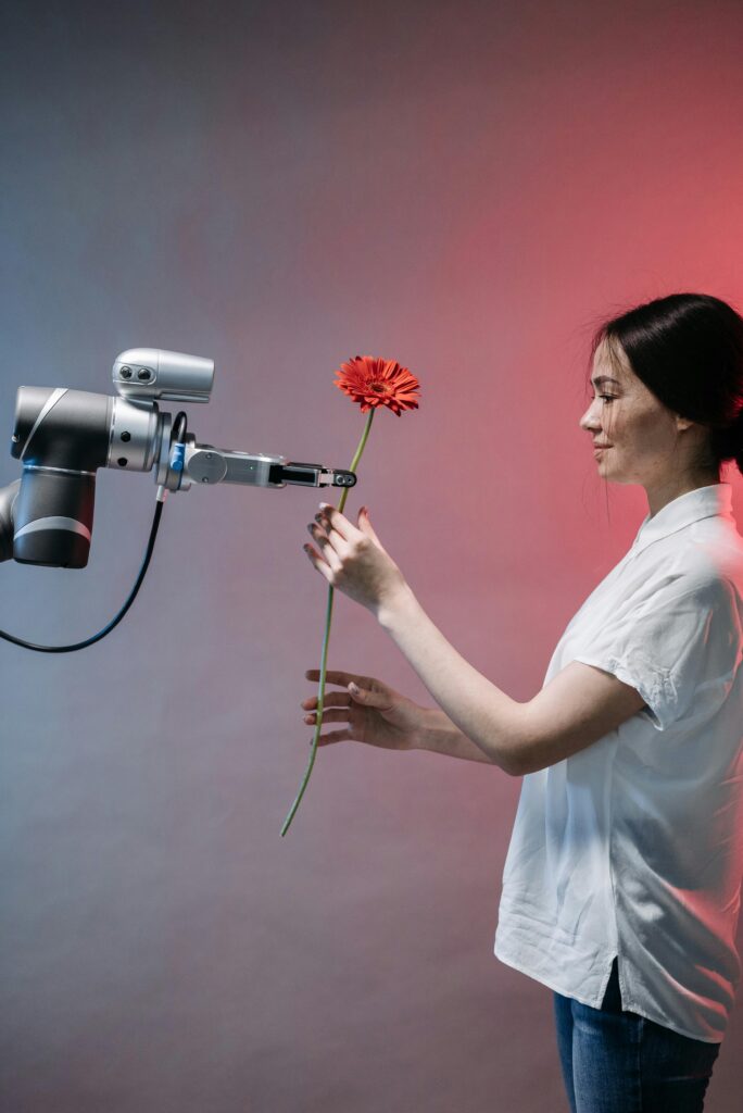 A woman is accepting a flower from a robot. 