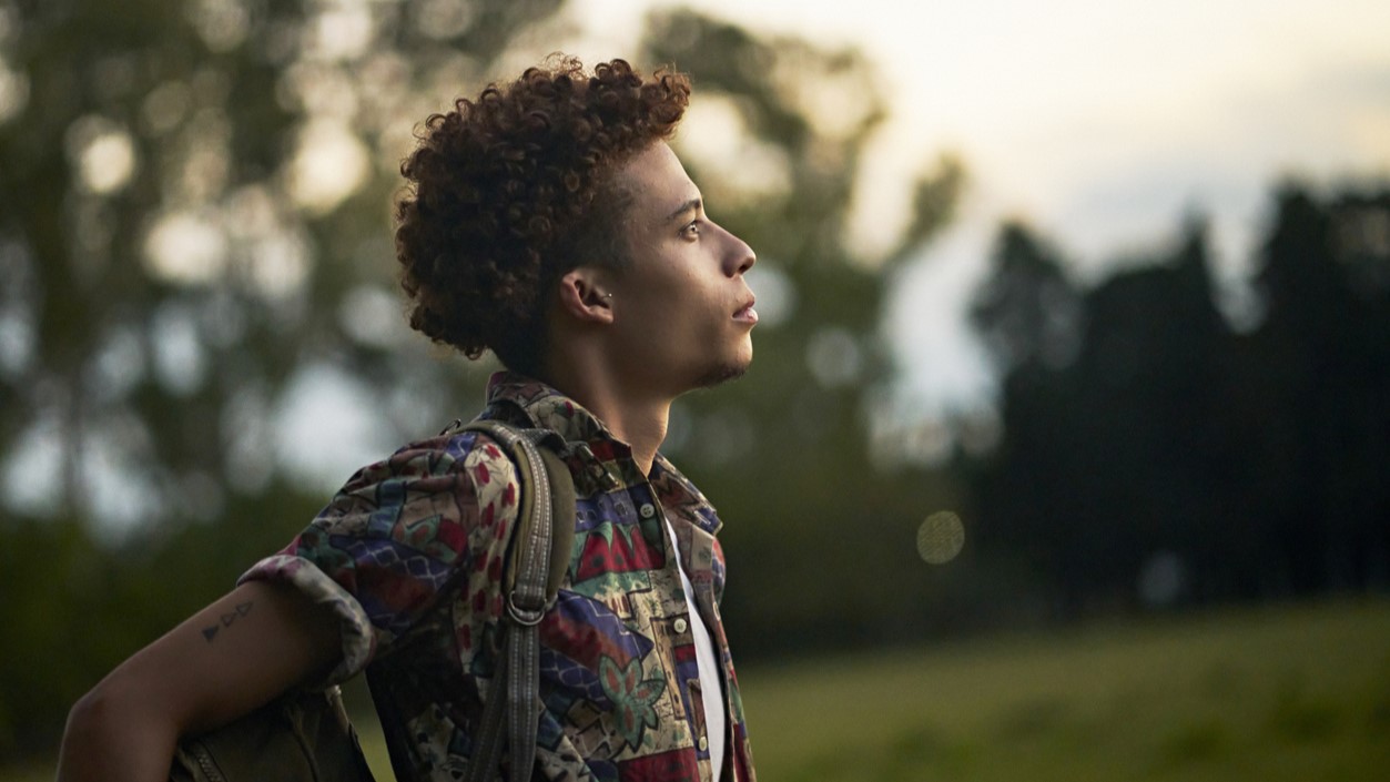 A young African American outdoors at dusk alone