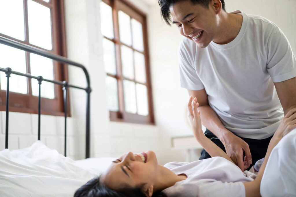 Asian couple having a tickling session on a bed