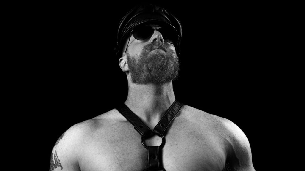 Man wearing a leather harness, a hat, and sunglasses