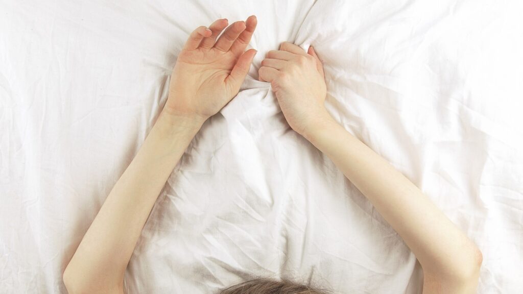 a woman's arm above her head in bed