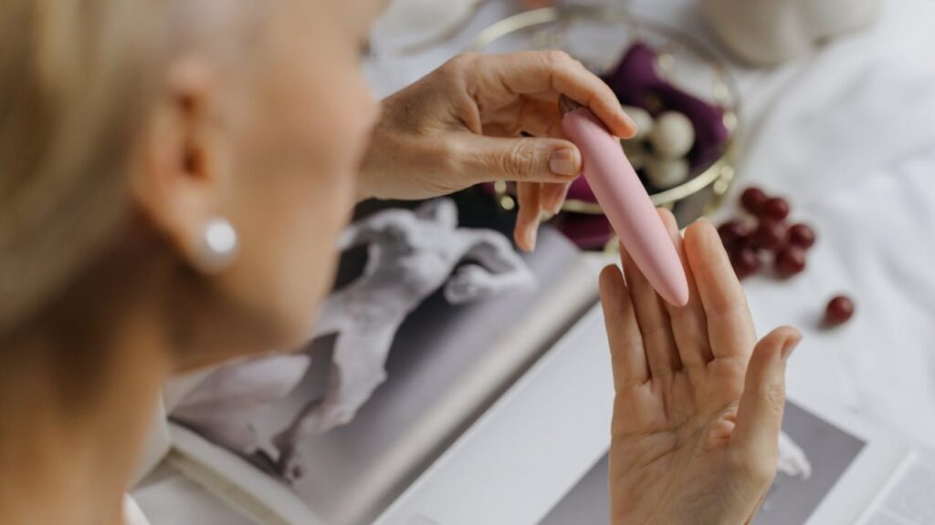 older white woman holding a pink sex toy at a desk