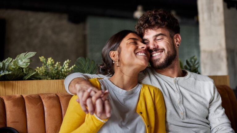 Cute couple smiling sitting next to each other and embracing