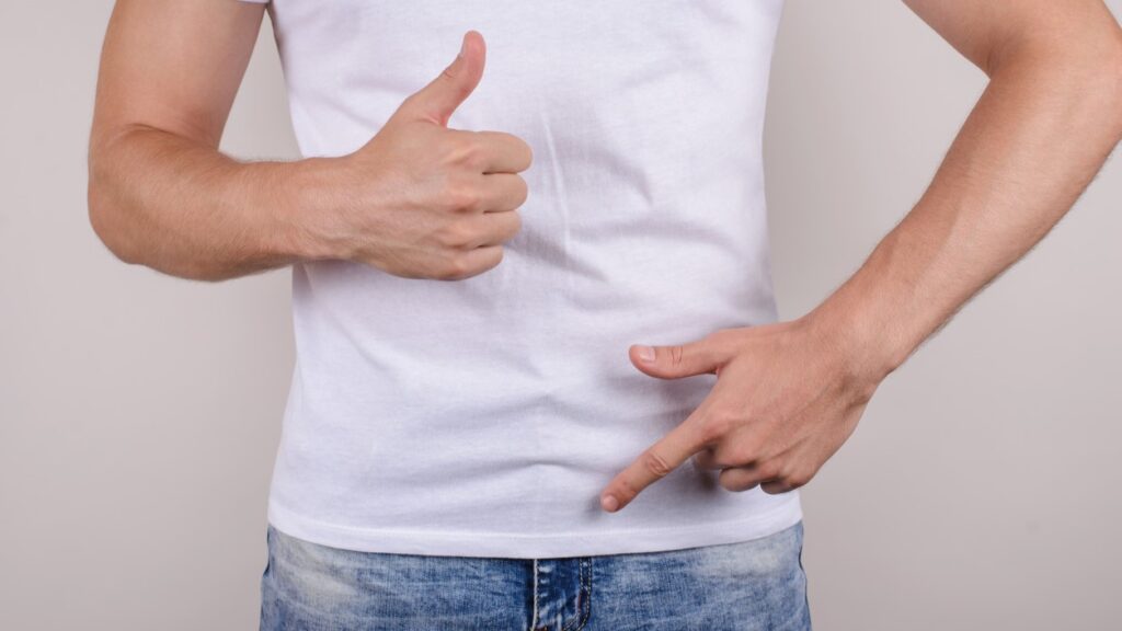 Man giving thumbs up and point at groin with other hand