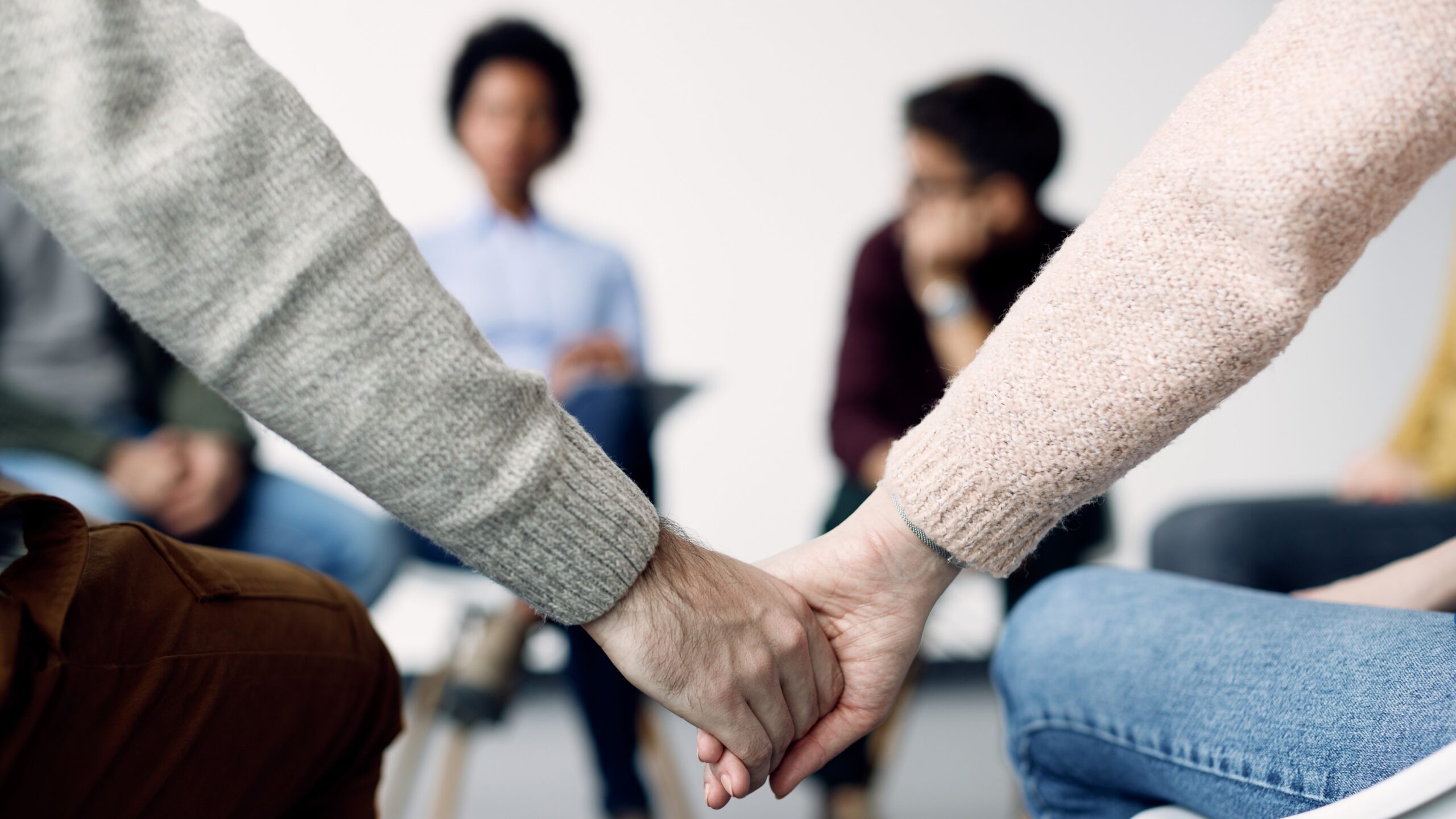 Close-up of two people holding hands during group sex therapy for couples