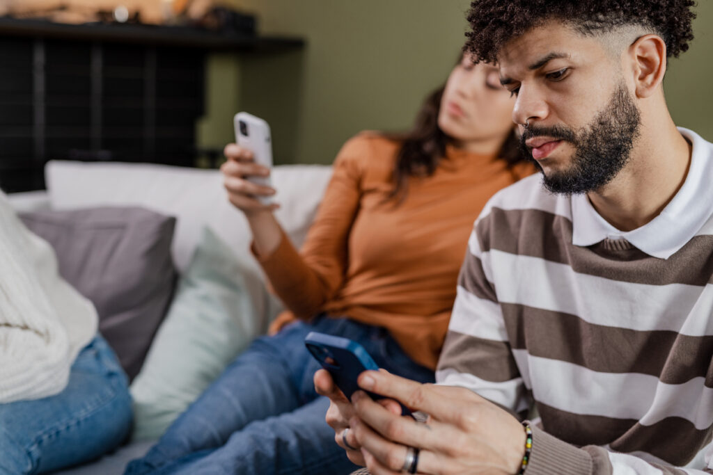 A couple are self-distracting during an argument by scrolling through their phones.