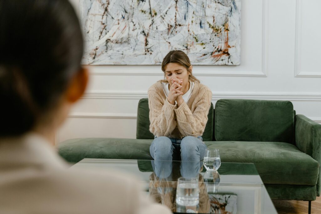 young woman sits in therapy and looks distressed.