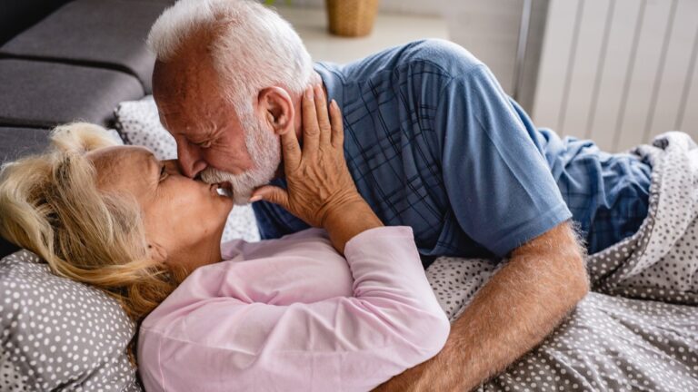 Older white senior couple kissing in bed