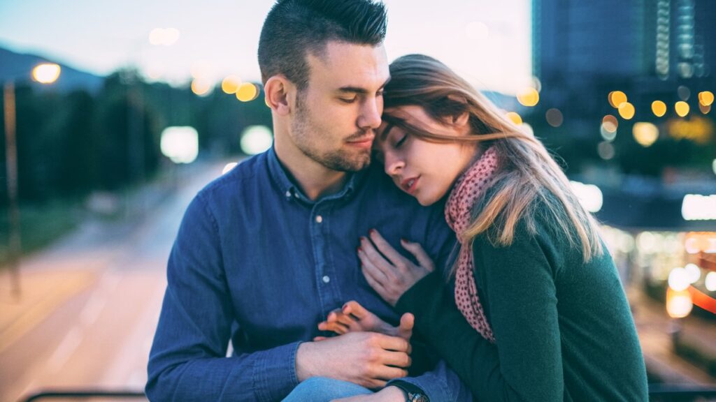 young couple cuddle in a cityscape