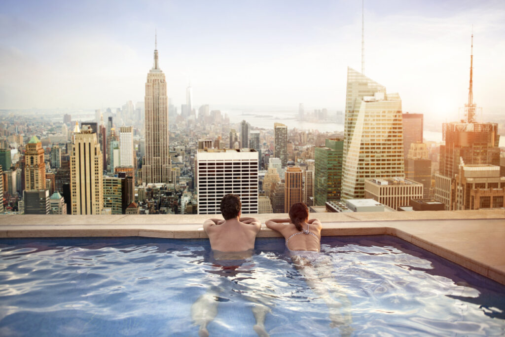 A couple in a rooftop pool looks out at the New York horizon A couple in a rooftop pool looks out at the New York horizon