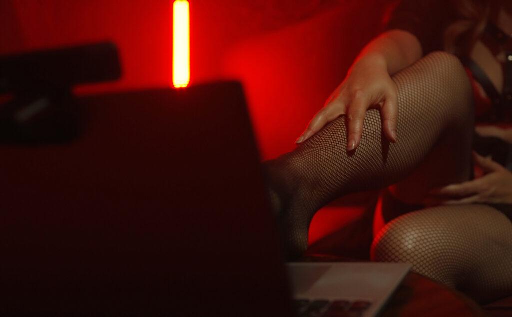 webcam model working on her laptop. she's wearing fishnets and showing off her feet.