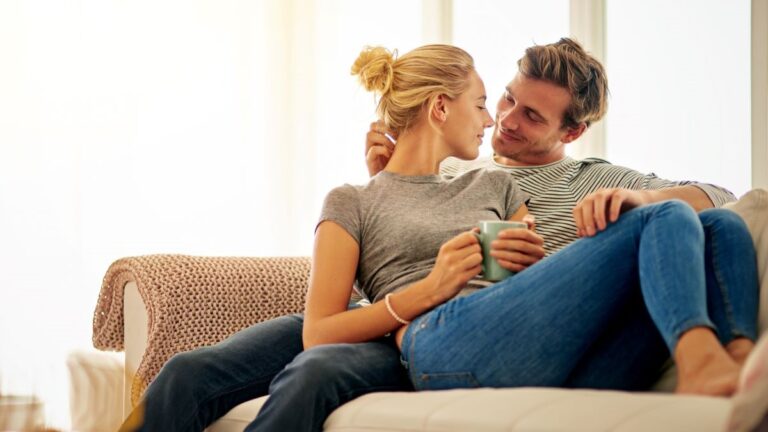 Young white couple on couch cuddling and looking like they are about to kiss