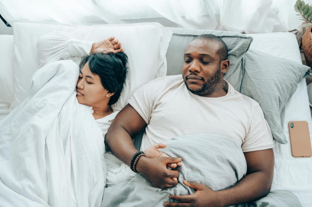 young multi-ethnic spouses sleeping in bed holding hands