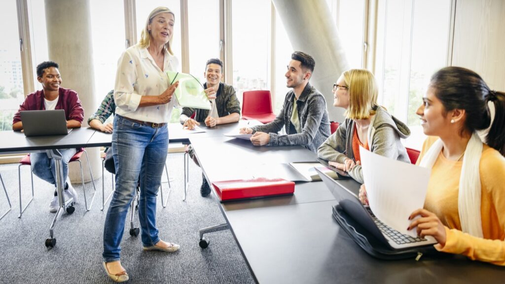 Students sitting in a classroom as the teacher stands