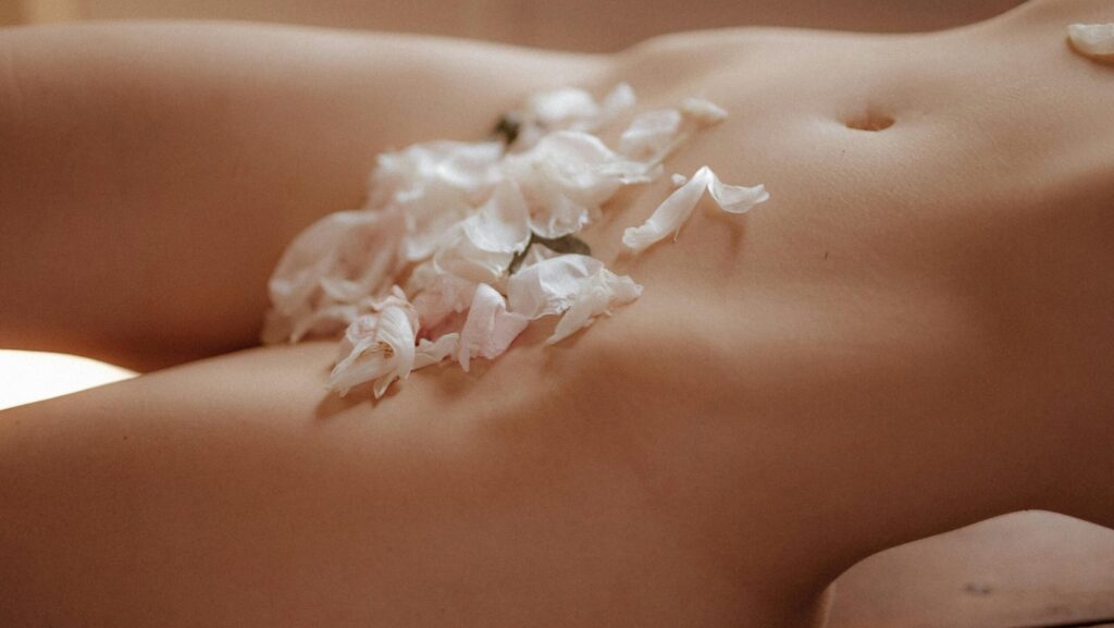 naked woman with flower petals covering parts of her body