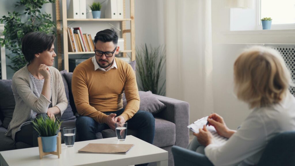 a couple sitting on a couch talking to a therapist