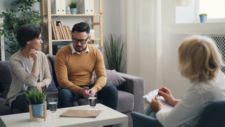 a couple sitting on a couch talking to a therapist