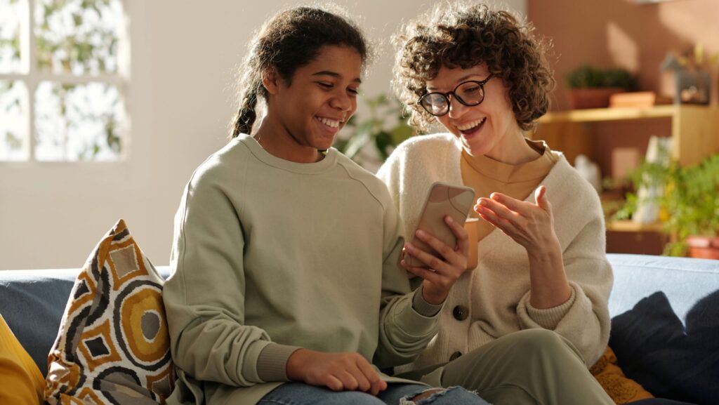 mom spending time with her daughter looking at a digital sex education app on their smartphone