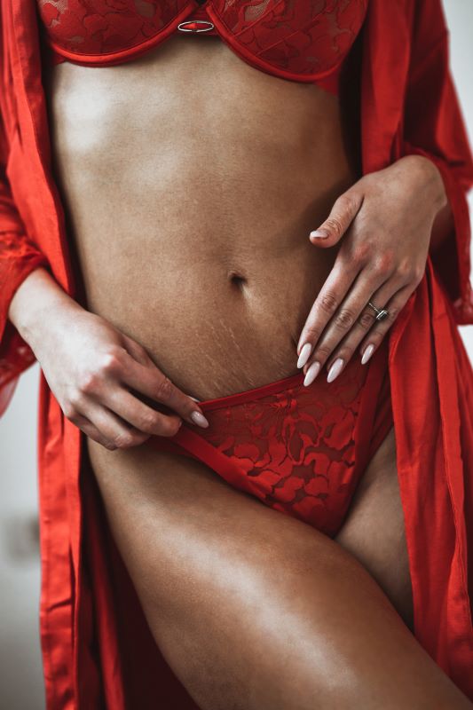 woman in red lingerie postpatrum with stretch marks on stomach