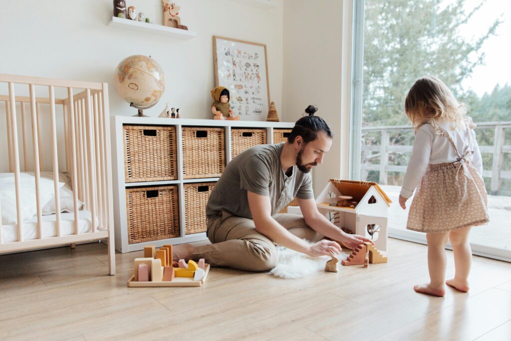 dad playing with a dollhouse with is daughter in her room.